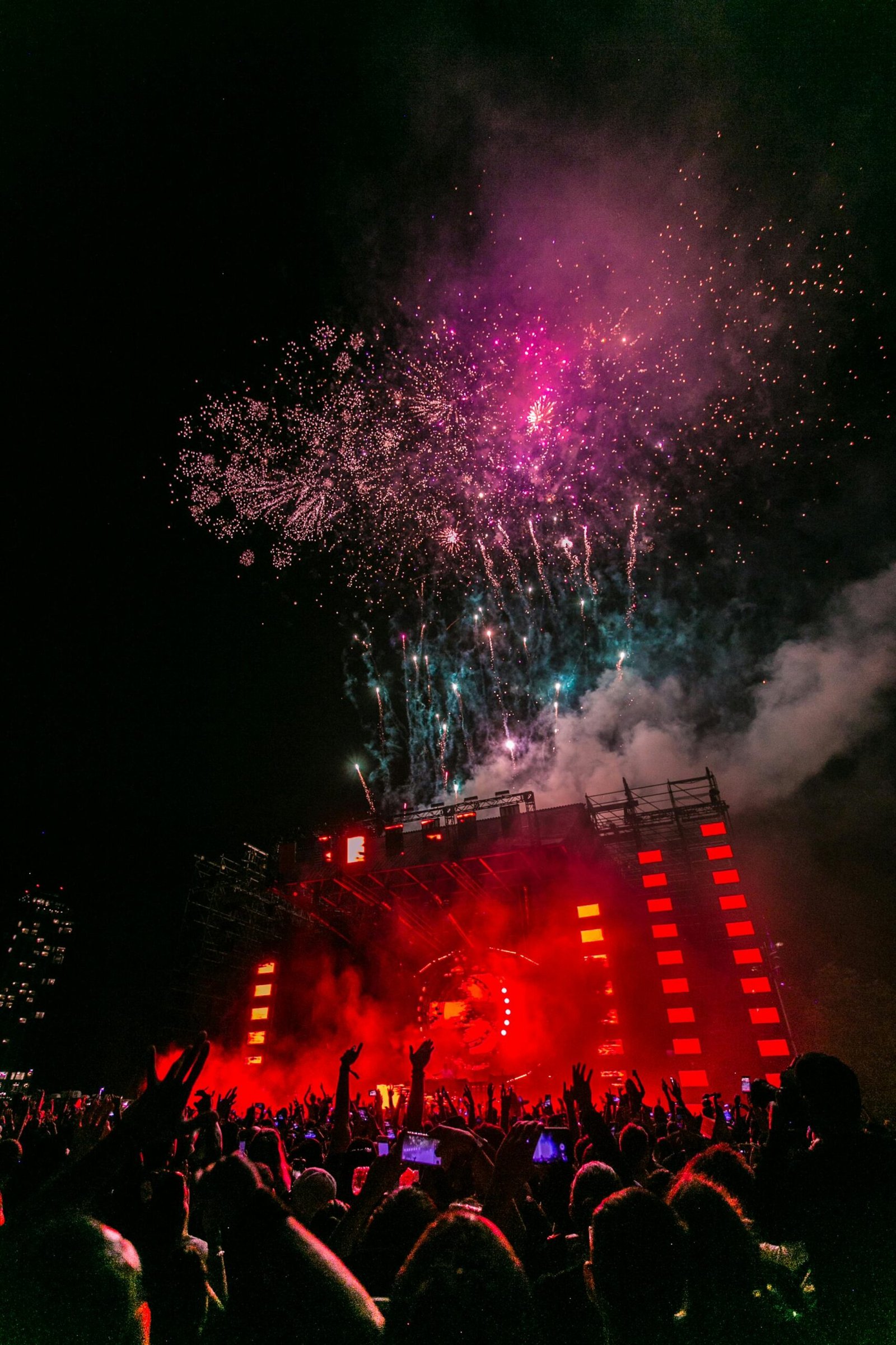 Energetic outdoor concert at night with a vibrant fireworks display and crowd enjoying live music.